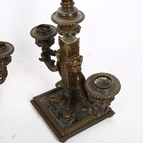 513 - A pair of ornate cast-brass 2-branch table candelabras, with flame finials and dolphin supports on a... 