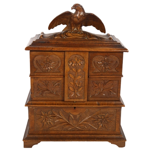 522 - A Black Forest carved oak jewellery box, with a rising lid, 4 pull-out drawers, surmounted by an eag... 