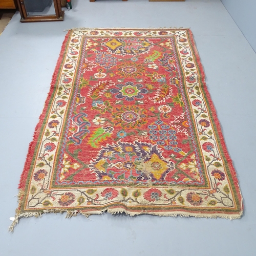 2314 - A red-ground Persian style wool rug with floral decorated medallion. 210x125cm.