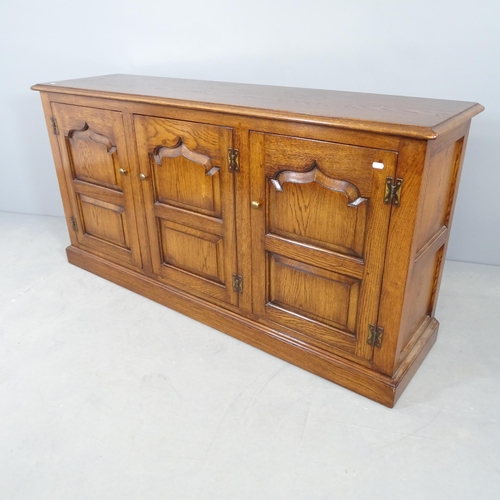 2696 - A reproduction oak dresser base, with three fielded panelled doors and shelved interior. 153x79x42cm... 