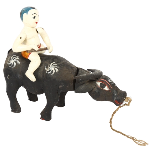 683 - A carved and painted wood Oriental water buffalo and rider, L30cm