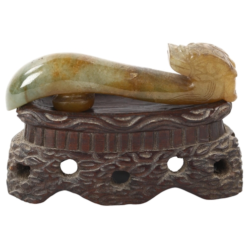 84 - A Chinese carved jade dragon design buckle on hardwood stand, length 8cm