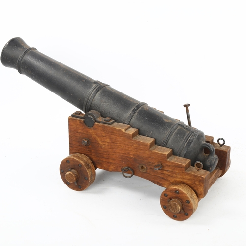 95 - A Victorian iron table cannon on wheeled wooden carriage base, barrel length 39cm