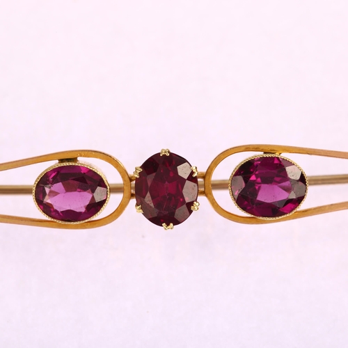 1179 - A large early 20th century three stone amethyst openwork bar brooch, unmarked gold settings with ova... 