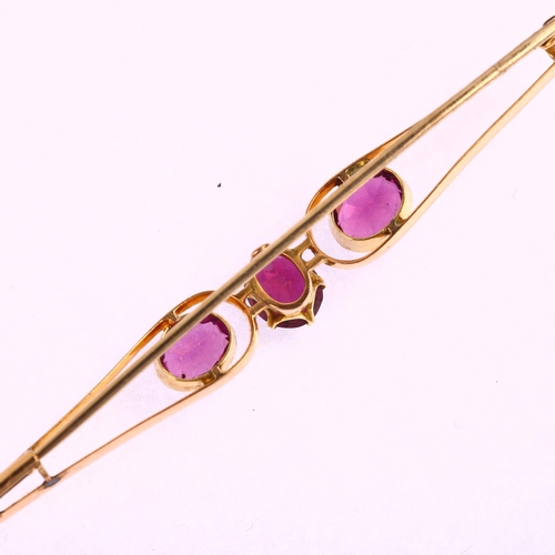 1179 - A large early 20th century three stone amethyst openwork bar brooch, unmarked gold settings with ova... 