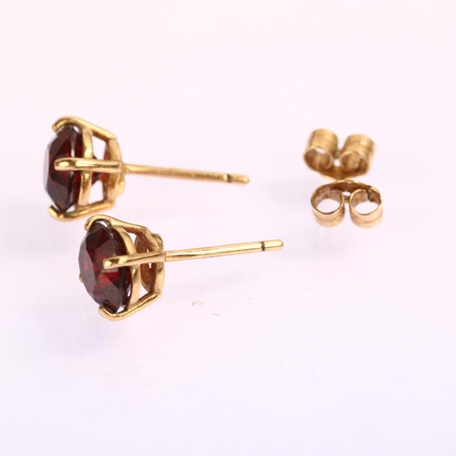 1224 - A pair of solitaire garnet earrings, unmarked yellow metal settings with stud fittings, garnet diame... 