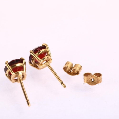 1224 - A pair of solitaire garnet earrings, unmarked yellow metal settings with stud fittings, garnet diame... 