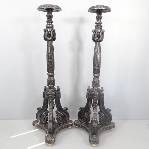 2110 - A pair of ebonised contintental torchere stands With carved decoration, tripod legs and platform bas... 