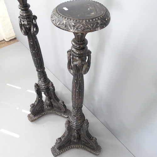 2110 - A pair of ebonised contintental torchere stands With carved decoration, tripod legs and platform bas... 