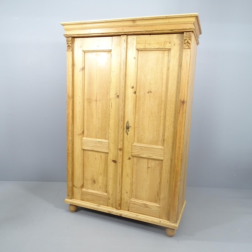 2129 - A pine two-door wardrobe, with rail fitted interior and raised on bun feet. 113x177x54cm