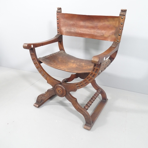 2195 - An antique oak Savonarola chair with carved decoration and studded leather seat.