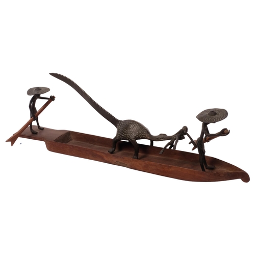 296 - Circa 1920s, a Nigerian bronze fishing group depicting fishermen paddling while their comrade is bei... 