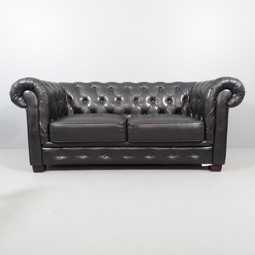 2050 - A black button back faux-leather upholstered two seater Chesterfield sofa. Overall 188x80x90cm, seat... 