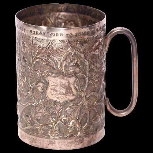 1010 - A Chinese white metal mug, with embossed and repousse floral decoration, with inscription to the top... 