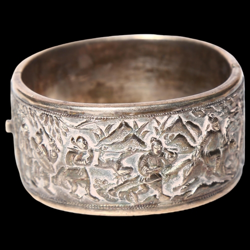 1013 - A Chinese embossed silver hinged bangle, panels decorated with hunting figures, with maker's mark fo... 