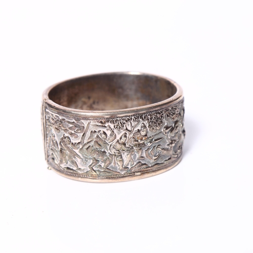 1013 - A Chinese embossed silver hinged bangle, panels decorated with hunting figures, with maker's mark fo... 