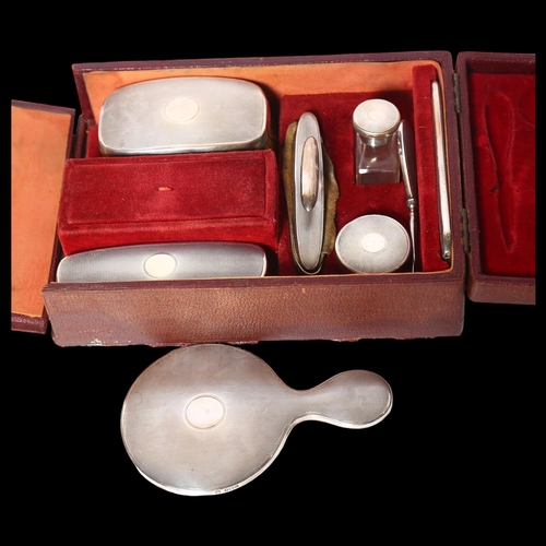 961 - A George V engine turned silver-backed travelling leather vanity case, comprising a small hand mirro... 