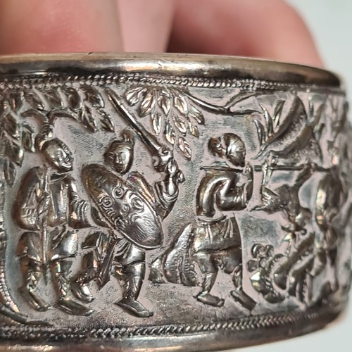 1013 - A Chinese embossed silver hinged bangle, panels decorated with hunting figures, with maker's mark fo... 