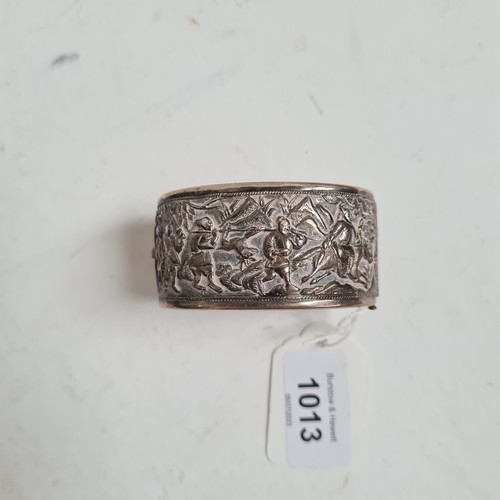 1013 - A Chinese embossed silver hinged bangle, panels decorated with hunting figures, with maker's mark fo... 