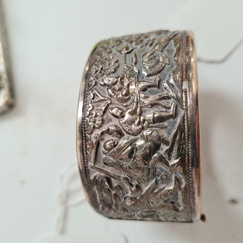 1013 - A Chinese embossed silver hinged bangle, panels decorated with hunting figures, with maker's mark fo... 