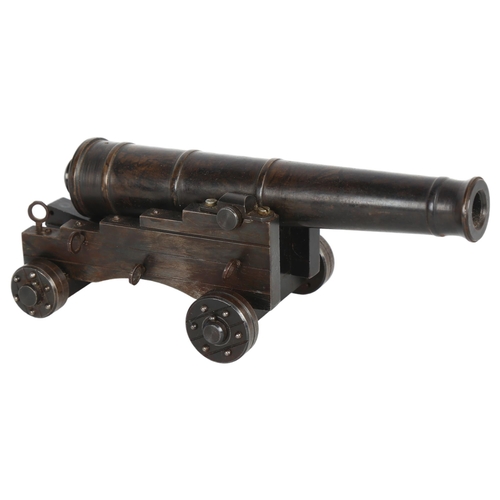 196 - A patinated bronze table cannon, on wheeled steel carriage base, overall length 19cm