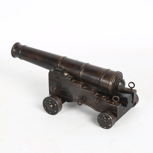 196 - A patinated bronze table cannon, on wheeled steel carriage base, overall length 19cm