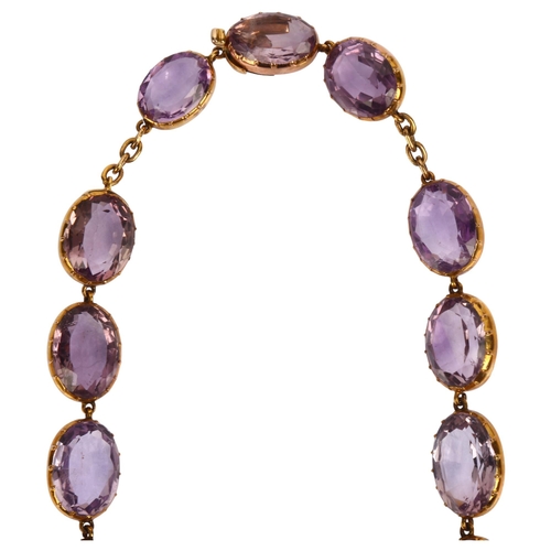 1104 - A Victorian amethyst Riviere necklace, the graduated oval amethysts set in unmarked gold cut-down co... 