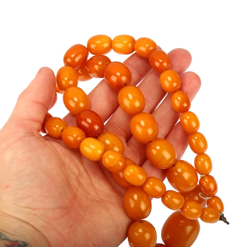 1127 - A single-strand graduated butterscotch amber bead necklace, bead lengths ranging from 25.8 - 11.5mm,... 