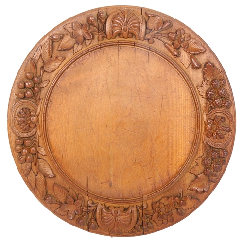 16 - A 20th century turned wood bread board, with applied leaf and floral decoration, diameter 32cm
