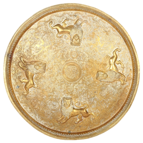 18 - An Indian brass circular tray, with repousse lions and engraved scrolled decoration, diameter 38.5cm