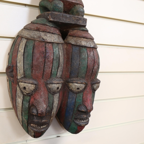 44 - A West African carved and painted double face mask, surmounted by a fertility figure, L70cm