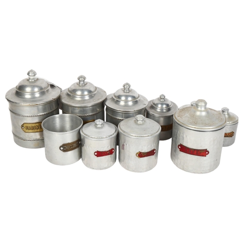 779 - A graduated set of 4 French aluminium storage jars and covers with brass plaques, a similar set of h... 