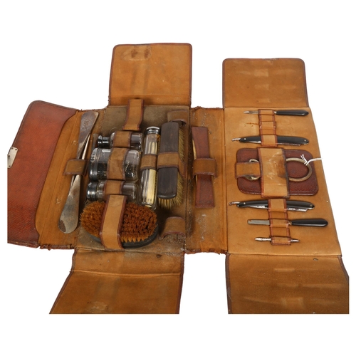 781 - A leather-cased gent's travelling set, including cut-throat razors, glass jars with silver tops, bru... 