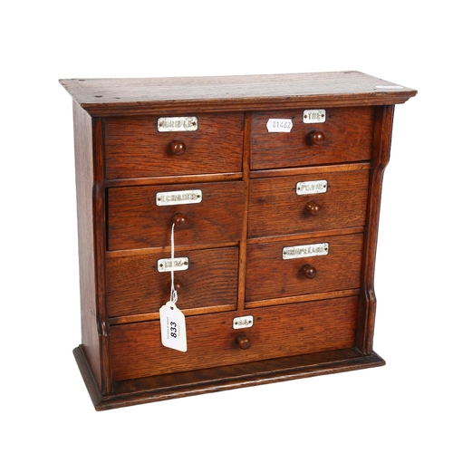 833 - An early 20th century oak table-top chest of 7 drawers, with aluminium name plates, including Girofl... 