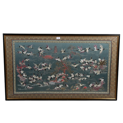 177 - A Chinese silk embroidered picture, depicting storks on a lake, machine embroidered surround, framed... 