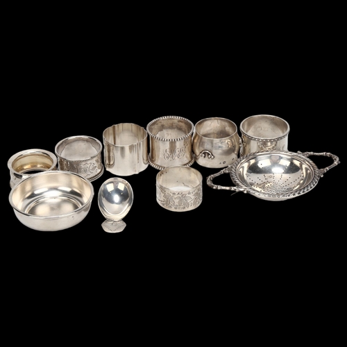 1444 - A group of various silver napkin rings, a George III silver caddy spoon, and a plated tea strainer o... 