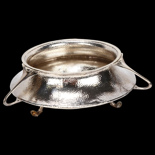 1470 - An Edward VII Arts and Crafts hammered circular silver fruit bowl, with 3 stylised handles on 3 scro... 