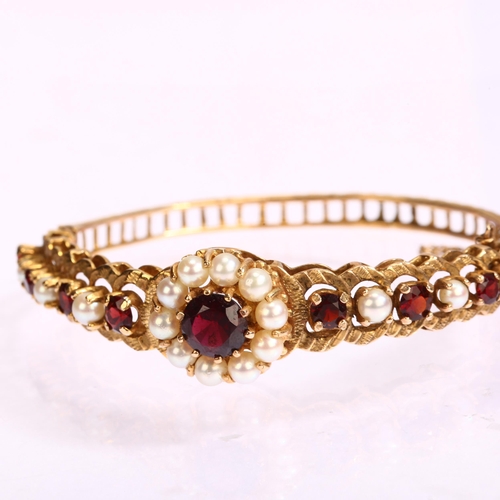 1131 - A mid-20th century 9ct gold garnet and pearl cluster hinge bangle, with central flowerhead cluster f... 