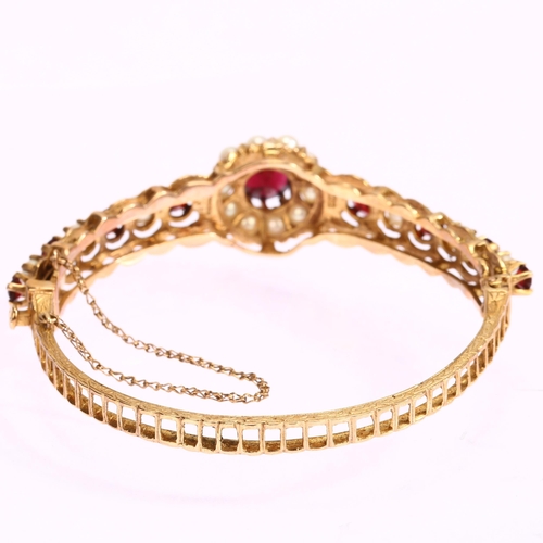 1131 - A mid-20th century 9ct gold garnet and pearl cluster hinge bangle, with central flowerhead cluster f... 