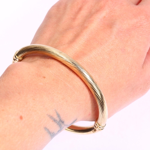 1135 - A 9ct gold hinged bangle, ribbed and polished decoration, band width 6mm, internal circumference app... 