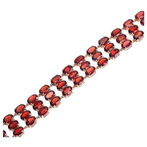 1165 - A modern 9ct gold garnet and diamond triple-row line bracelet, set with oval mixed-cut garnets, band... 