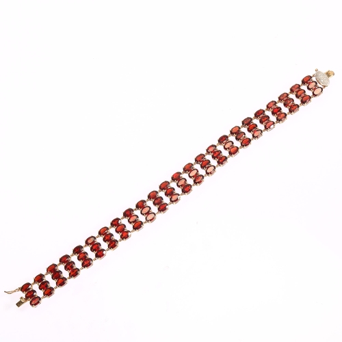 1165 - A modern 9ct gold garnet and diamond triple-row line bracelet, set with oval mixed-cut garnets, band... 