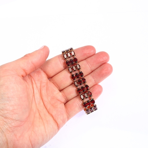 1165 - A modern 9ct gold garnet and diamond triple-row line bracelet, set with oval mixed-cut garnets, band... 