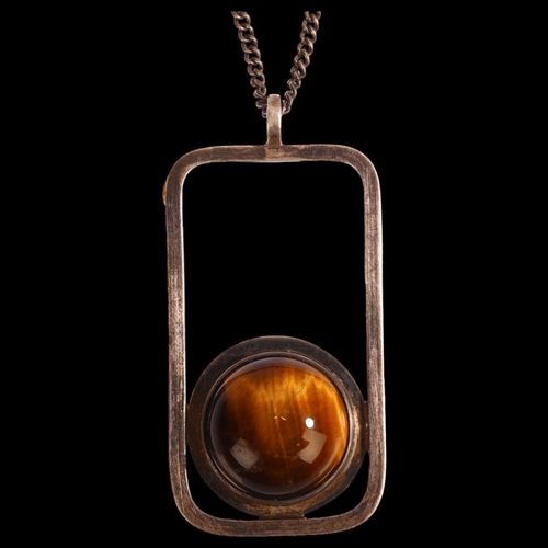 1306 - A Scottish modernist silver and cabochon tigers eye set abstract pendant on silver chain, marked KND... 