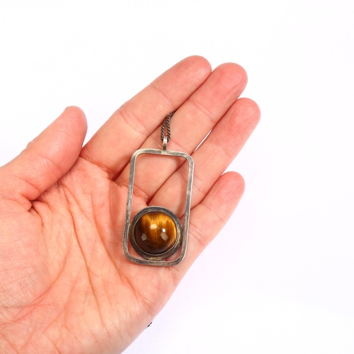 1306 - A Scottish modernist silver and cabochon tigers eye set abstract pendant on silver chain, marked KND... 