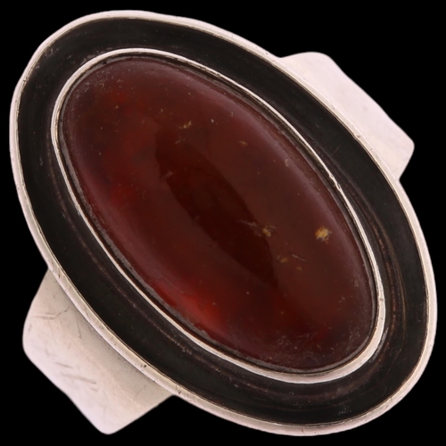 1347 - N E FROM - a Danish sterling silver ring set with oval amber panel, setting height 21mm, 5g