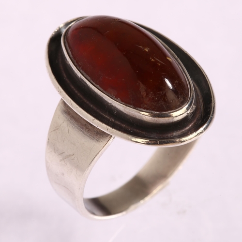 1347 - N E FROM - a Danish sterling silver ring set with oval amber panel, setting height 21mm, 5g