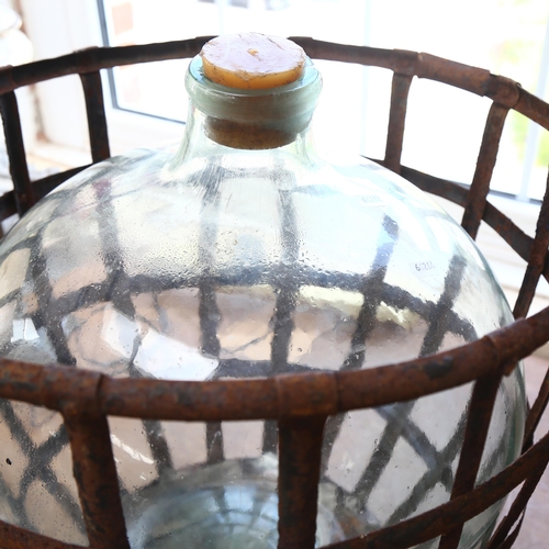 23 - A large green glass carboy in a pressed metal lattice surround, bottle height 52cm, overall height 5... 