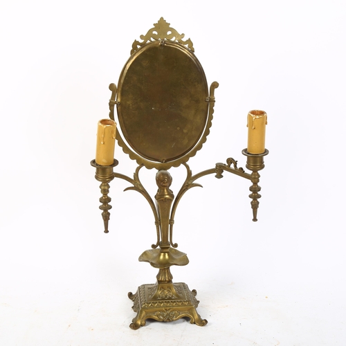 439 - A Vintage Continental oval brass swing toilet mirror, with figure support and candle lamps, H48cm