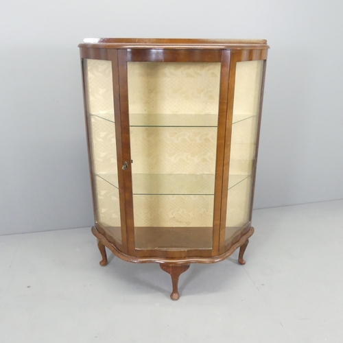 2587 - A 1930s walnut glazed display cabinet of serpentine form, with two fixed shelves and raised on cabri... 